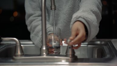 person holding clear glass container