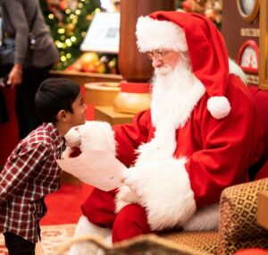 boy standing in front of man wearing Santa Claus costume